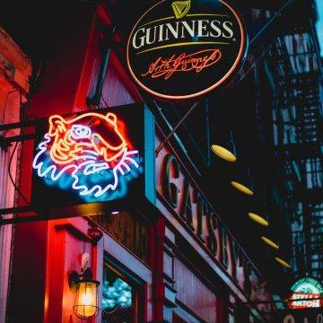 picture if a bar at night with a lit up Guinness sign